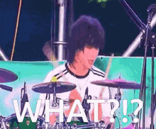 a man playing drums with the words " what ? " above him