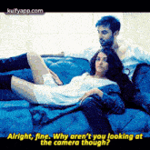 a man and a woman are laying on a blue couch and the woman is laying on the man 's lap