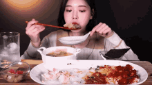 a woman is eating a plate of food with chopsticks and a spoon