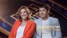 a man and a woman are sitting next to each other in front of a sign with hebrew writing on it