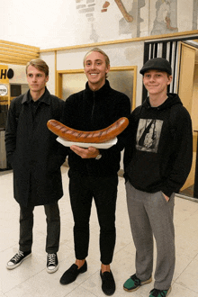 three young men standing next to each other with one wearing a black sweatshirt with a picture of a woman on it