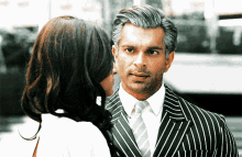 a man in a striped suit looks at a woman