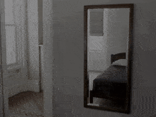 a man adjusts his tie in front of a large mirror