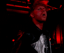a man wearing a black and white jacket is standing in front of red lights