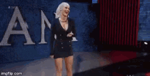a female wrestler is standing in a wrestling ring with her hands on her chest .