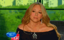 a woman is sitting in front of an american idol coca cola cup