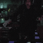 a man wearing headphones and holding a remote control in a dark room