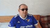 a man wearing sunglasses and a blue shirt that says mw dicas