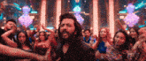 a man with a beard is dancing in front of a crowd of people in a club .