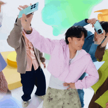 a man in a pink sweatshirt is holding a cell phone