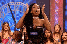 a woman in a black top is sitting in front of a crowd of women .