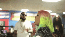 a woman with green hair stands in front of a sign that says queen of the ring