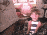 a boy in a striped shirt is standing in front of an open door with the letter b on the bottom right