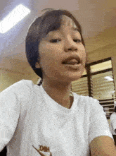 a young girl is taking a selfie in a classroom while wearing a white nike t-shirt .