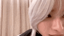 a close up of a person 's face with white hair and a black jacket .