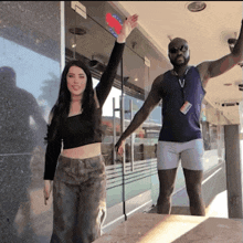 a man and a woman are standing in front of a building with a sign that says domino 's