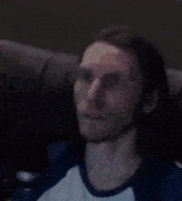 a man with long hair and a beard is sitting on a couch with his mouth open .