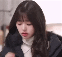 a close up of a girl with long hair and bangs wearing a black jacket and a white turtleneck .