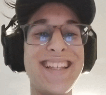 a man wearing headphones and glasses smiles for the camera