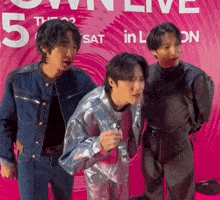 a group of young men are posing for a picture in front of a pink sign that says 5th sat in london .