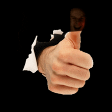 a hand is giving a thumbs up sign and a man is behind it