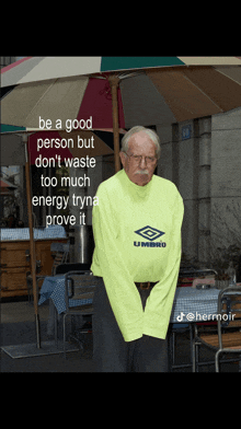 a man wearing a neon yellow umbro shirt stands under an umbrella