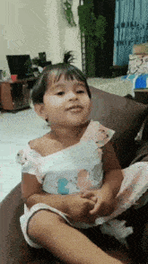 a little girl is sitting on a couch making a funny face .