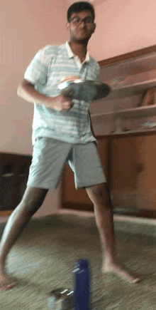 a man in a striped shirt and shorts is playing frisbee