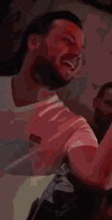a man with a ponytail and a beard is laughing and dancing in a club .
