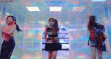 three women are dancing together in a room with a window .