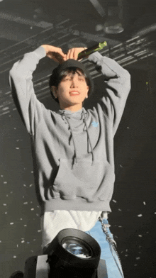 a young man wearing a grey hoodie is holding a microphone
