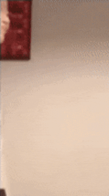 a blurred image of a person standing in front of a wall with a picture on it .