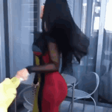a woman in a red dress is standing in front of a table and chairs