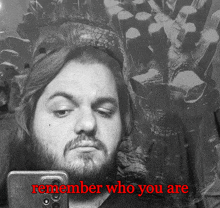 a man with a beard is taking a selfie with the words remember who you are above him
