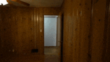 a man in a black shirt is standing in a hallway with a wooden wall .