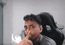 a man is sitting in a chair with his finger in his nose