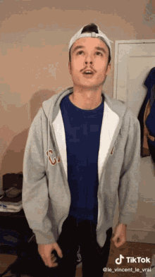 a man wearing a blue shirt and a gray hoodie has a tiktok watermark