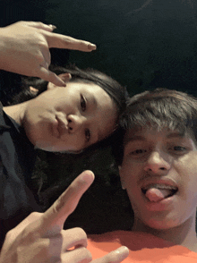 a boy and a girl are posing for a picture with their tongues out
