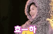 a woman wearing a furry hooded jacket with chinese writing on the bottom right corner
