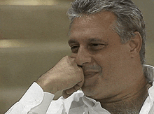 a man in a white shirt has his hand resting on his chin