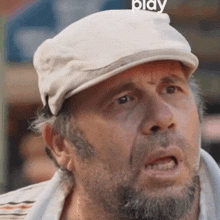a man with a beard is wearing a white hat and making a funny face