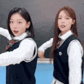 two girls are standing next to each other in front of a blackboard wearing school uniforms