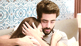 a man and a woman are hugging each other in a bedroom .