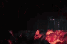 pennywise the clown from it is standing in a dark room surrounded by red balloons .