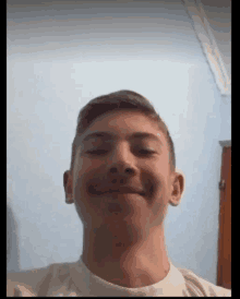 a young man in a white shirt is smiling and looking at the camera