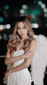 a woman in a white dress has angel wings on her shoulders