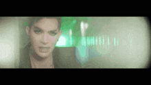 a close up of a woman 's face with a blurry background and a green light behind her .