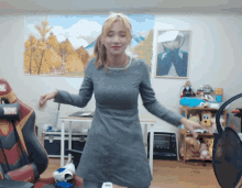 a woman in a grey dress is dancing in a room with a marvel chair