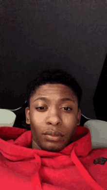 a young man wearing a red hoodie is laying down