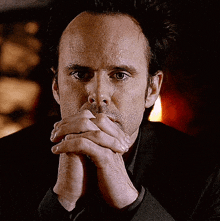a close up of a man 's face with his hands folded in front of his face